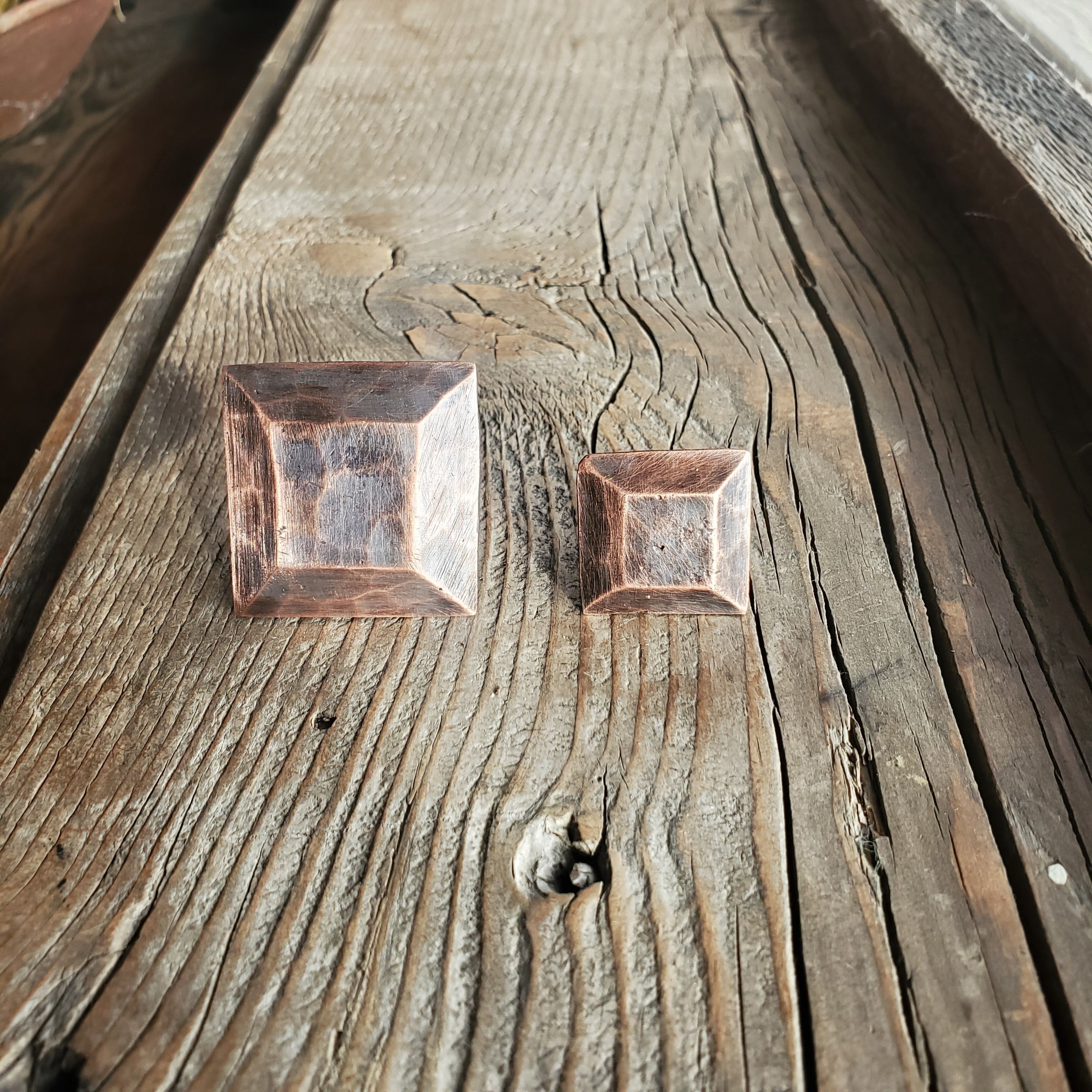 Two decorative clavo attachment types displayed on rustic wood surface