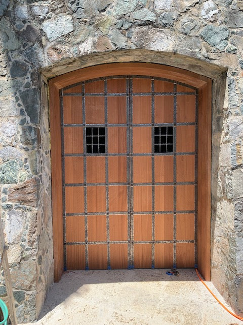 Rustic speakeasy door with decorative ironwork and stone archway entrance