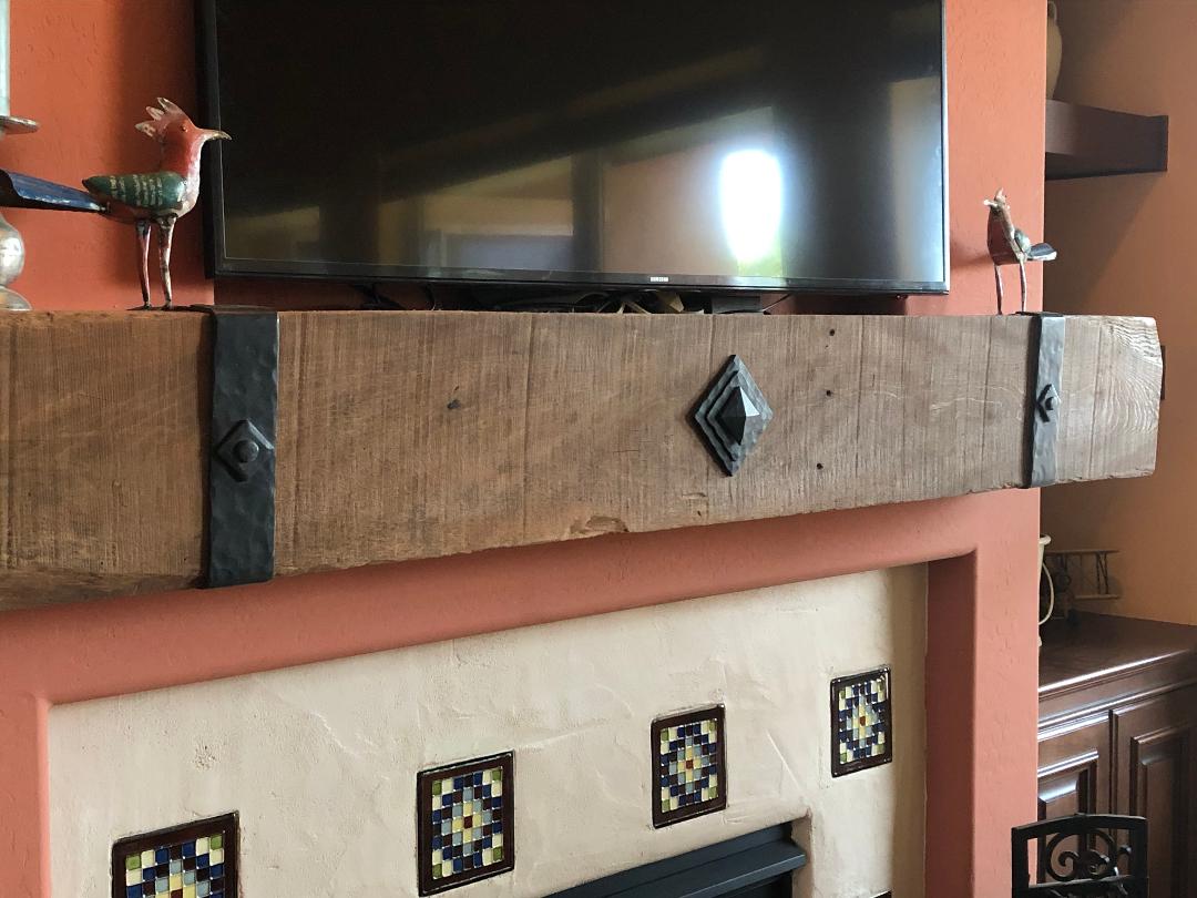 Rustic wooden fireplace mantel with metal straps and decorative birds on top