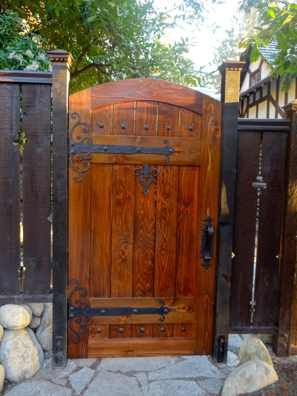 Sturdy wooden gate with decorative metal accents and serene garden backdrop