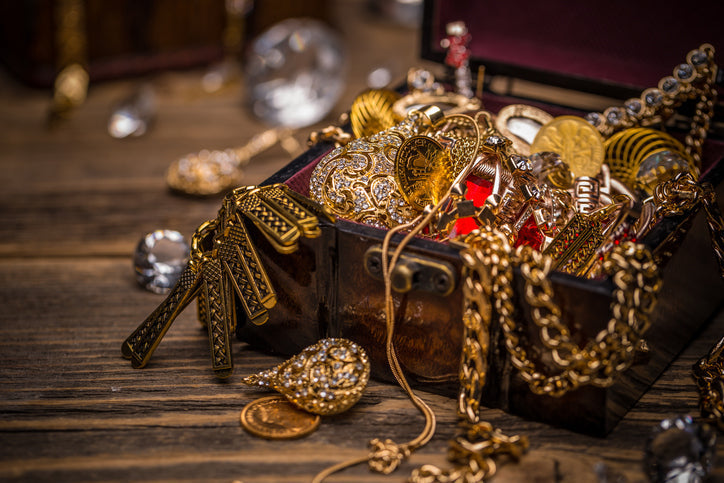 treasure chest filled with golden jewelry and ornate decorations on wooden surface