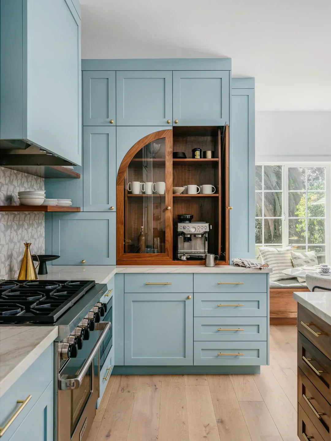 modern kitchen with blue cabinetry and open shelving showcasing coffee maker and mugs