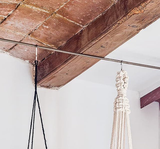 Close-up of a wooden beam with hanging rope decorations in a rustic interior setting