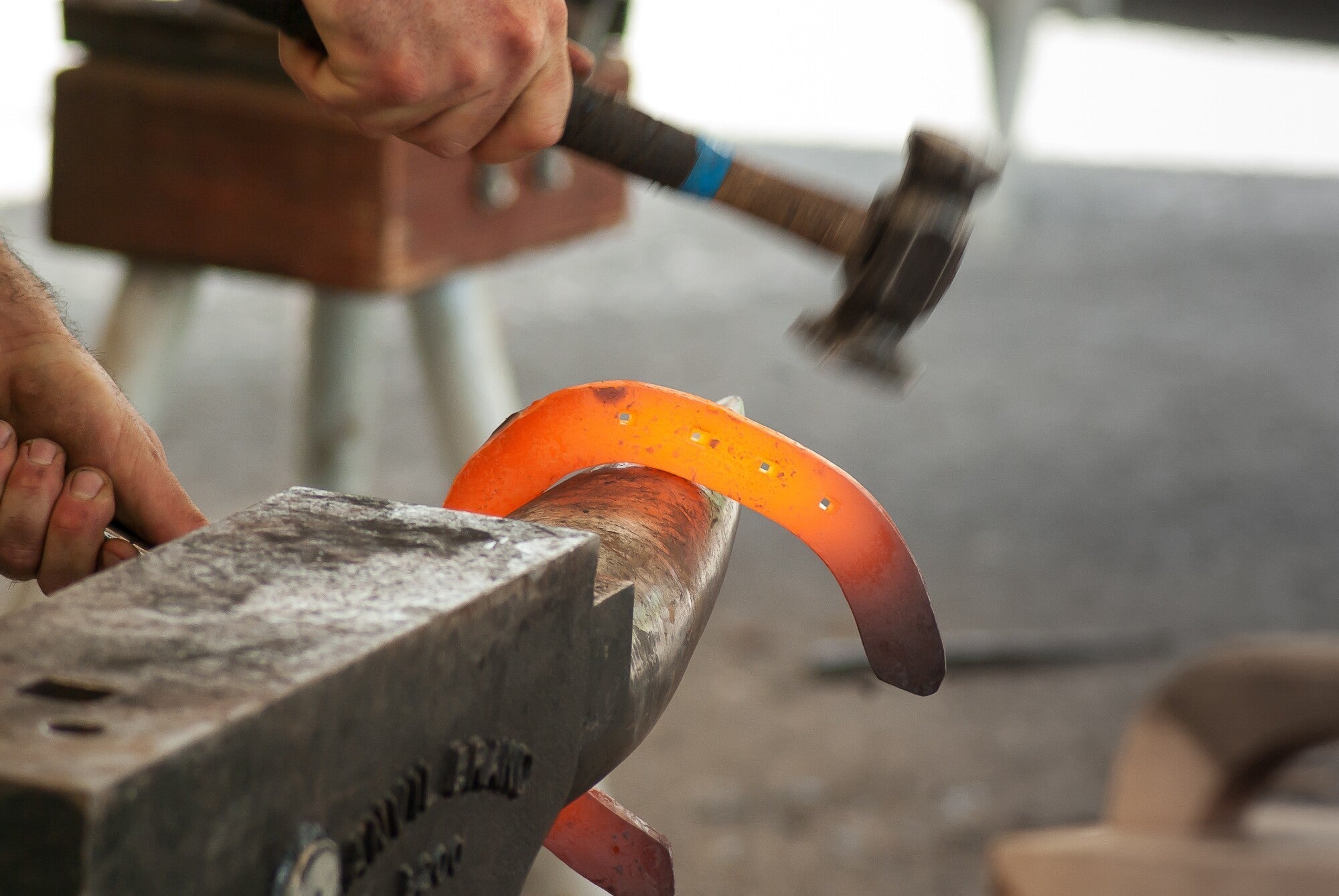 Blacksmith shaping a glowing horseshoe on an anvil with a hammer in hand