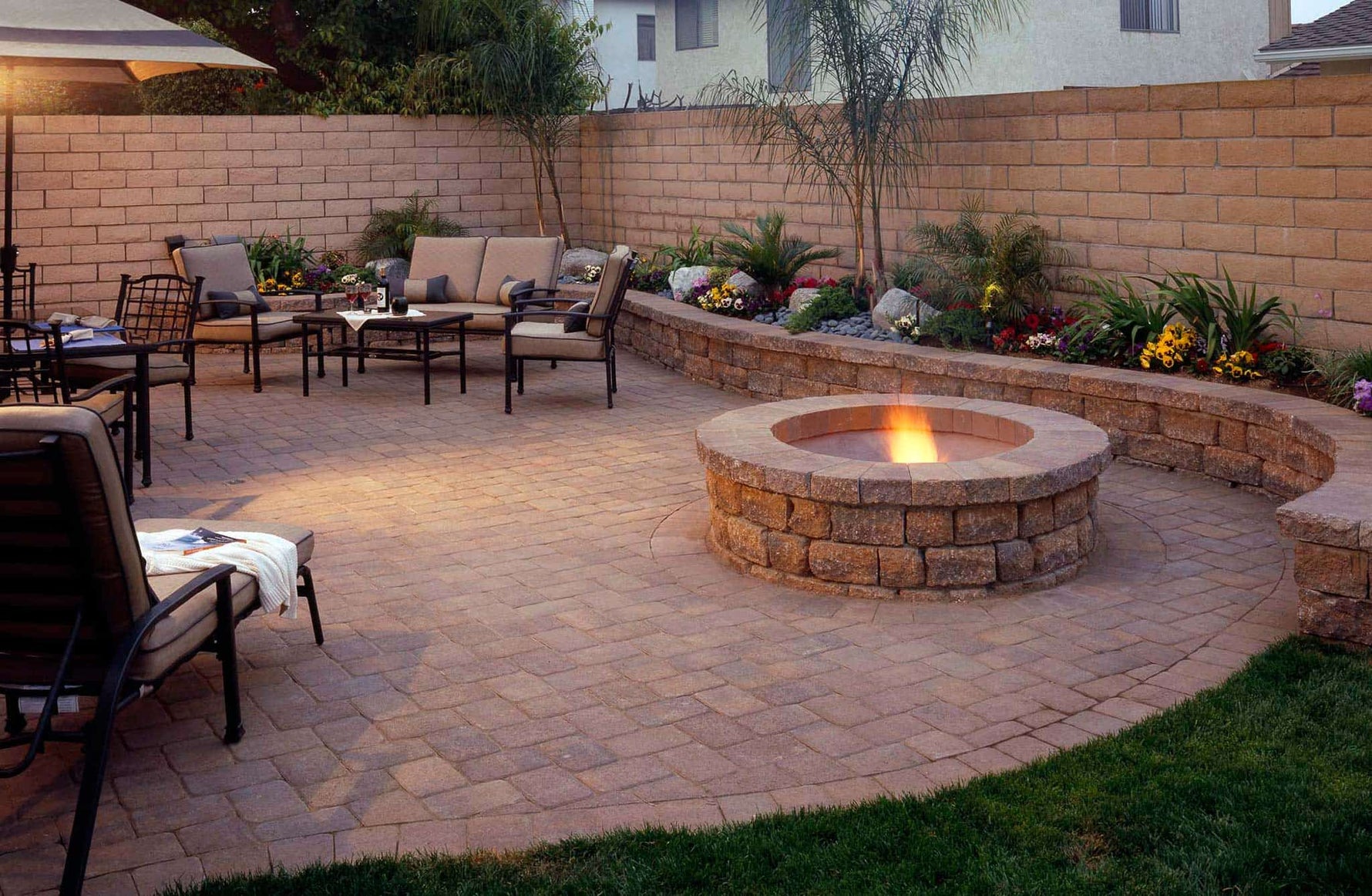 Cozy patio setup featuring a stone fire pit surrounded by rustic seating and vibrant flowers