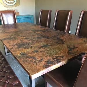 Elegant copper sheeting table with iron legs surrounded by leather chairs in modern setting