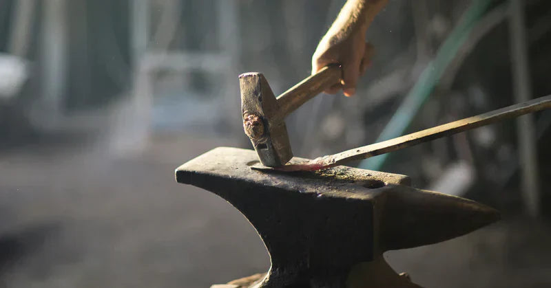 A blacksmith striking red-hot metal on an anvil, showcasing modern blacksmithing techniques