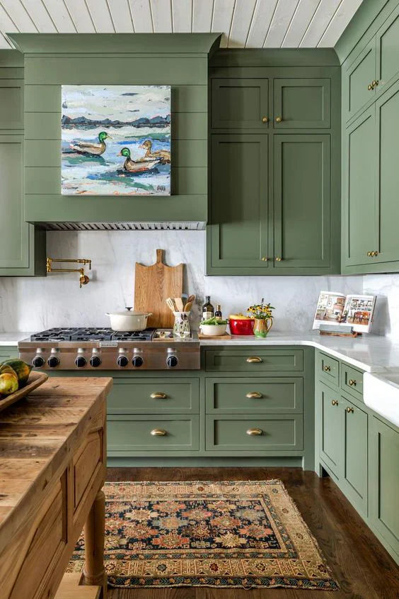 Modern kitchen featuring green cabinetry, gold hardware, and a decorative rug with nature-inspired art