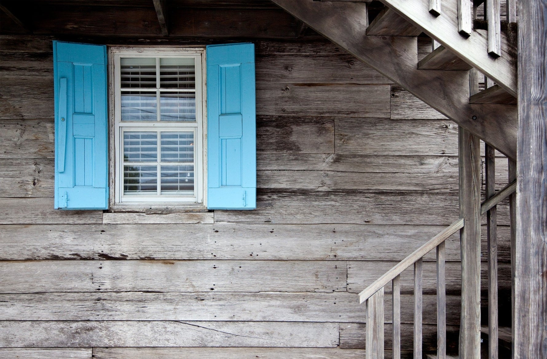 rustic wooden wall with blue shuttered window and wooden staircase accentuating charm