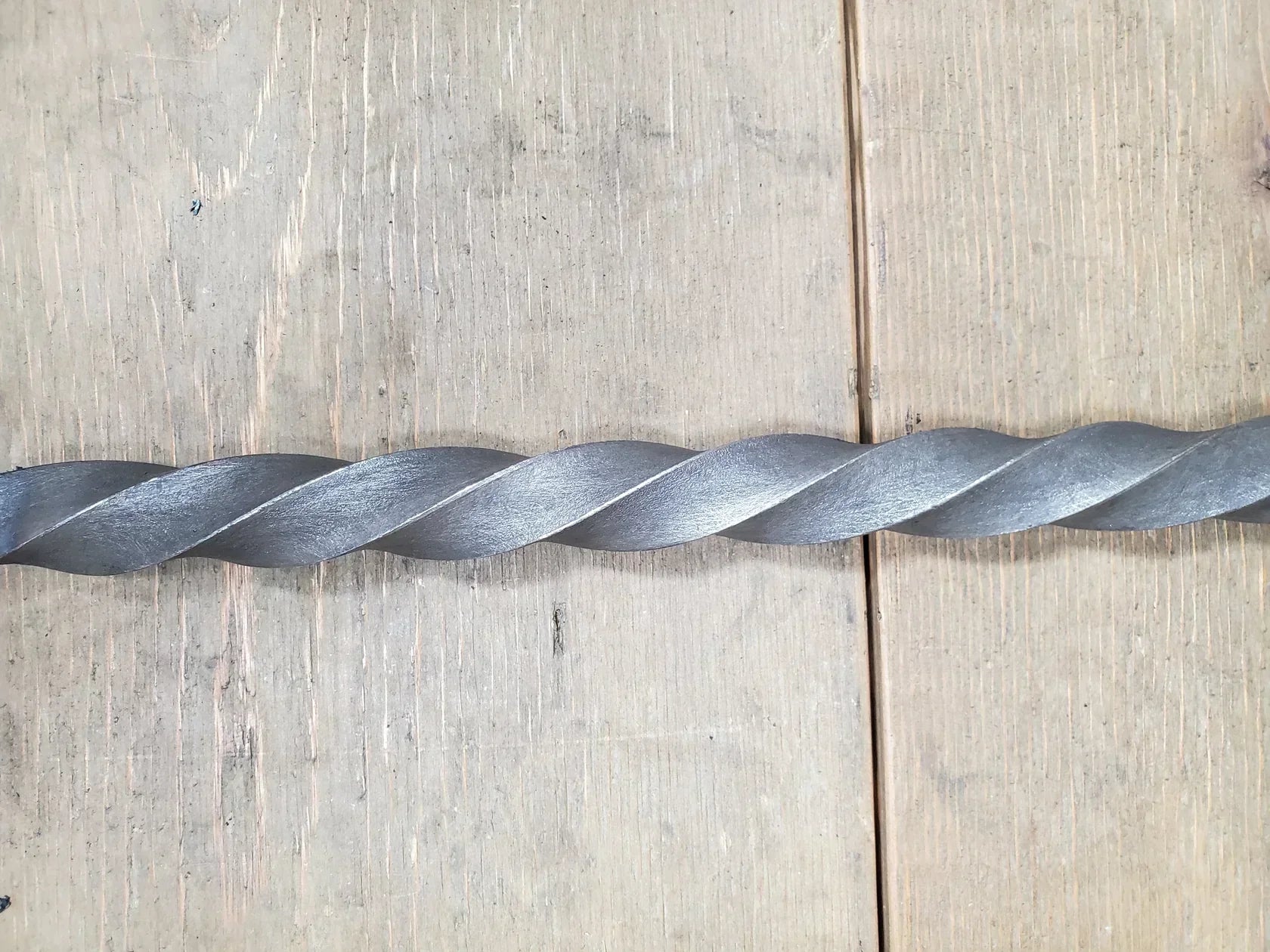 Twisted threaded rod on wooden surface, showcasing industrial design for various projects