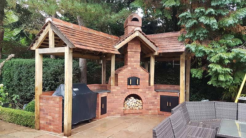 outdoor brick oven setup with wooden structure and stacked firewood for pizza making