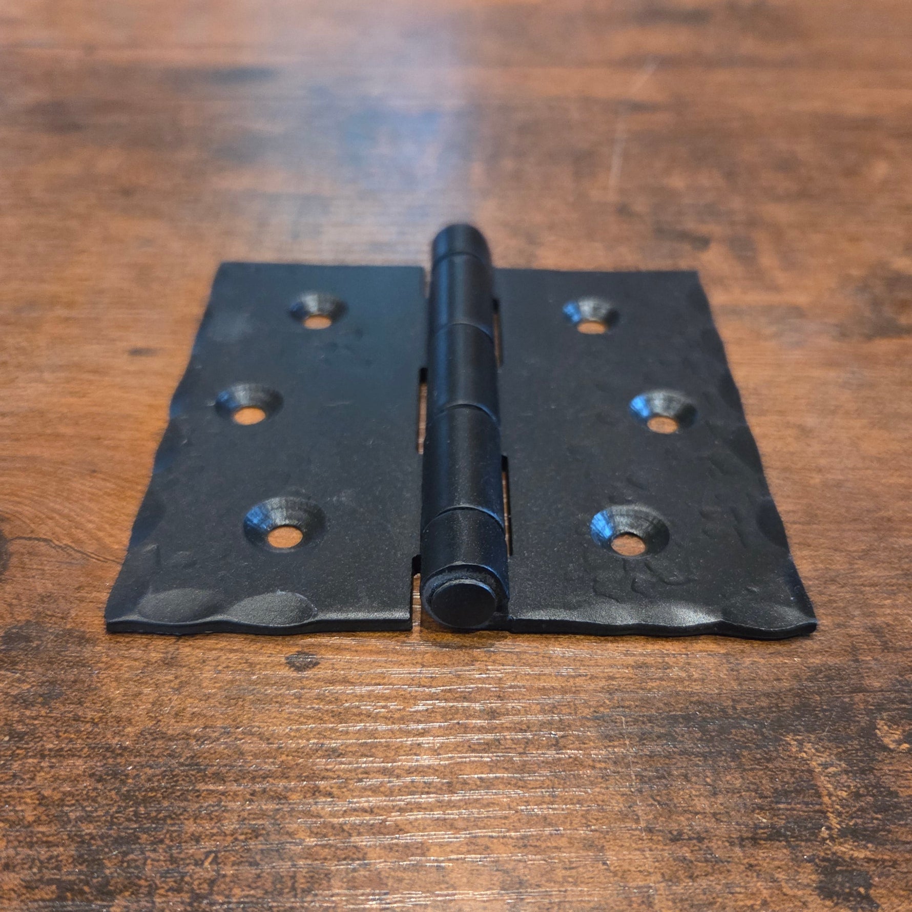 Black metal hinge on a wooden surface