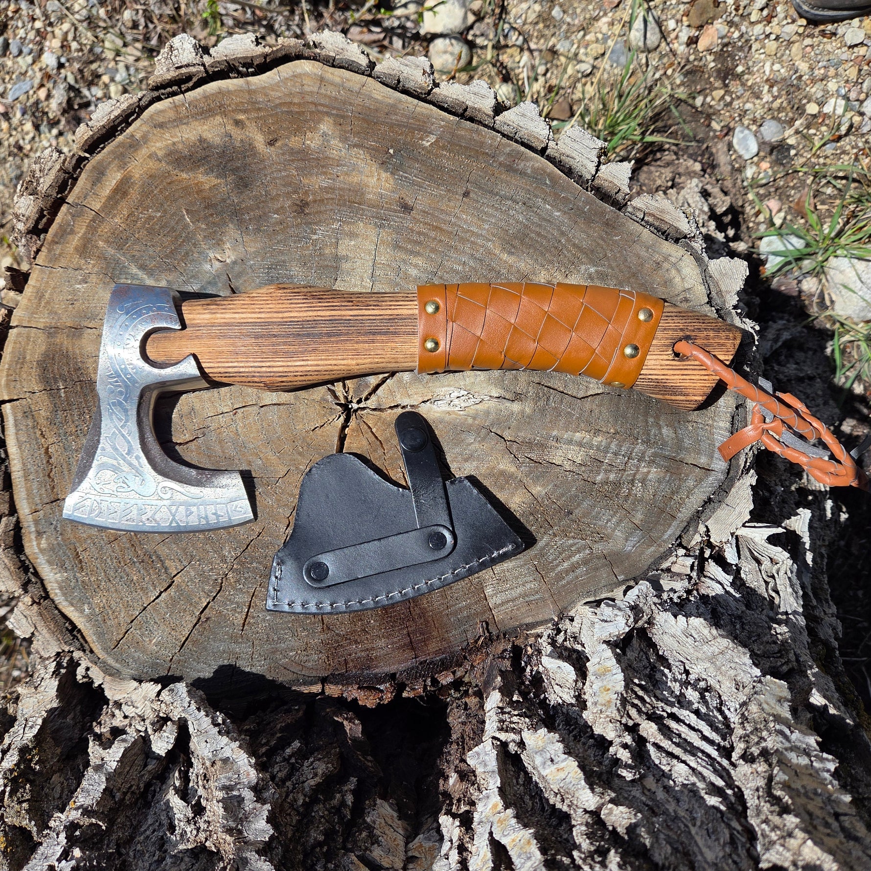 Axes with leather sheaths on a wooden stump outdoors