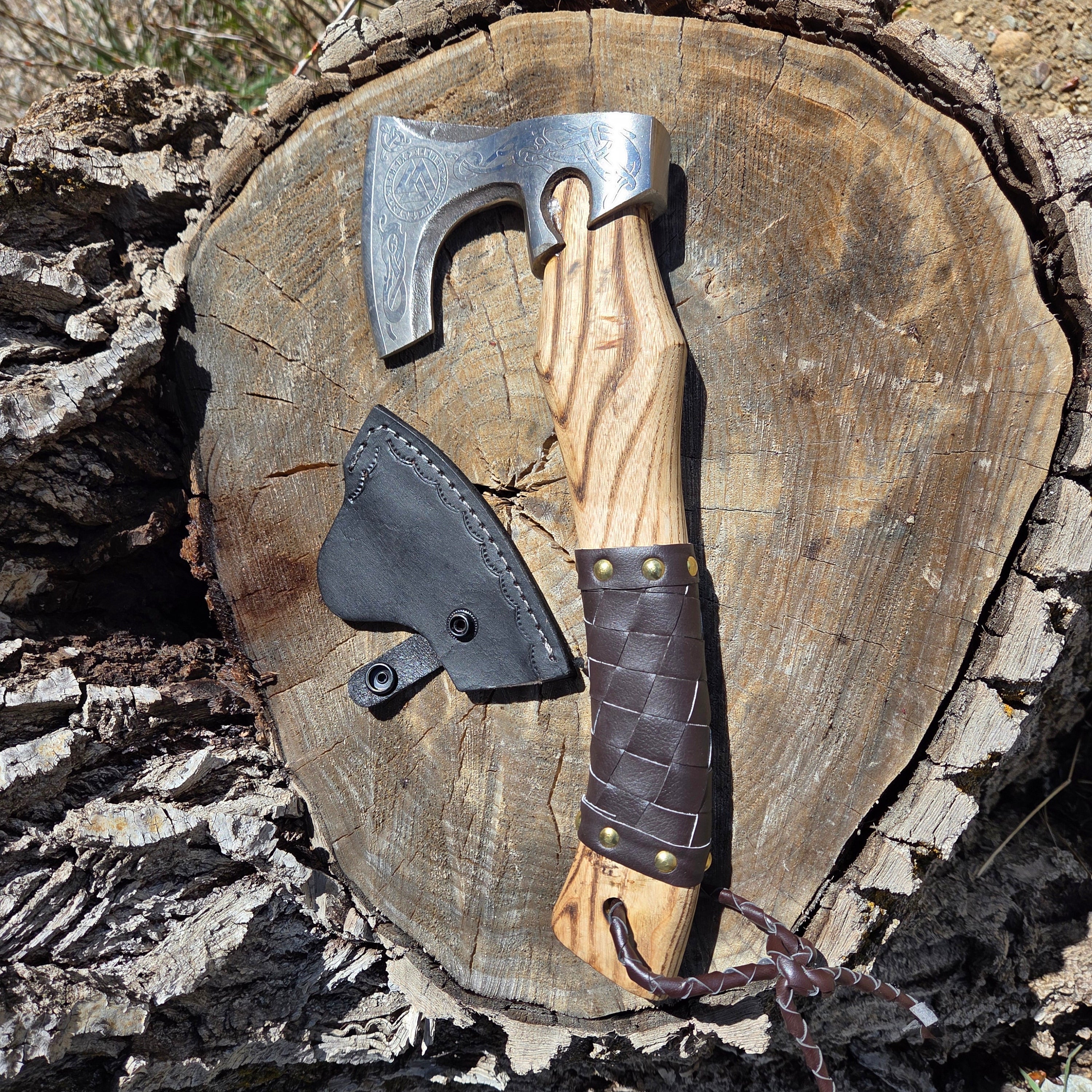 Wooden axe handle with leather grip on a tree stump