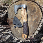 Wooden axe handle with leather grip on a tree stump