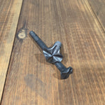 A hand hammered cross square head bolt with a wrought iron finish on a wood background.