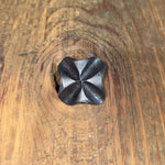 A hammered cross square head bolt that has a wrought iron finish on a wood background.
