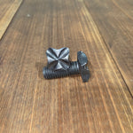 A decorative hammered cross square head bolt with a wrought iron finish on a wood background.