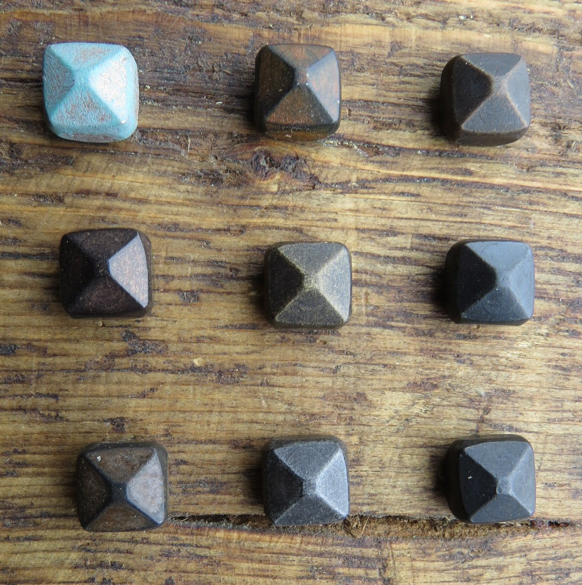 A n assortment of thick square pyramid head decorative screw on a wooden surface.