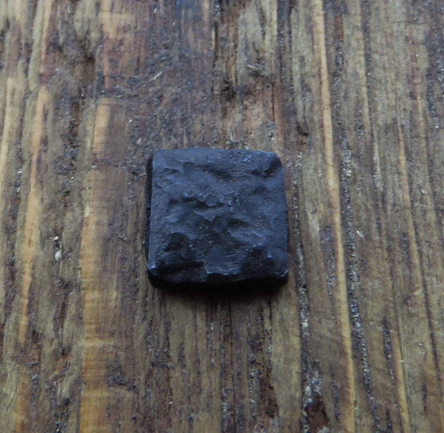 A black distressed textured square head lag in a piece of wood for the background