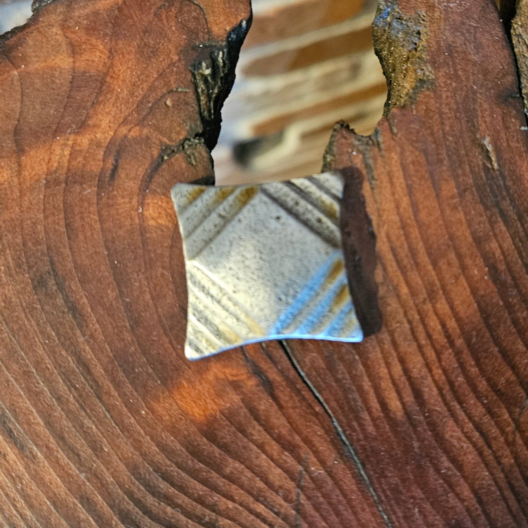 A top view of an ornate tapered square head bolt with a raw finish on a wood background.