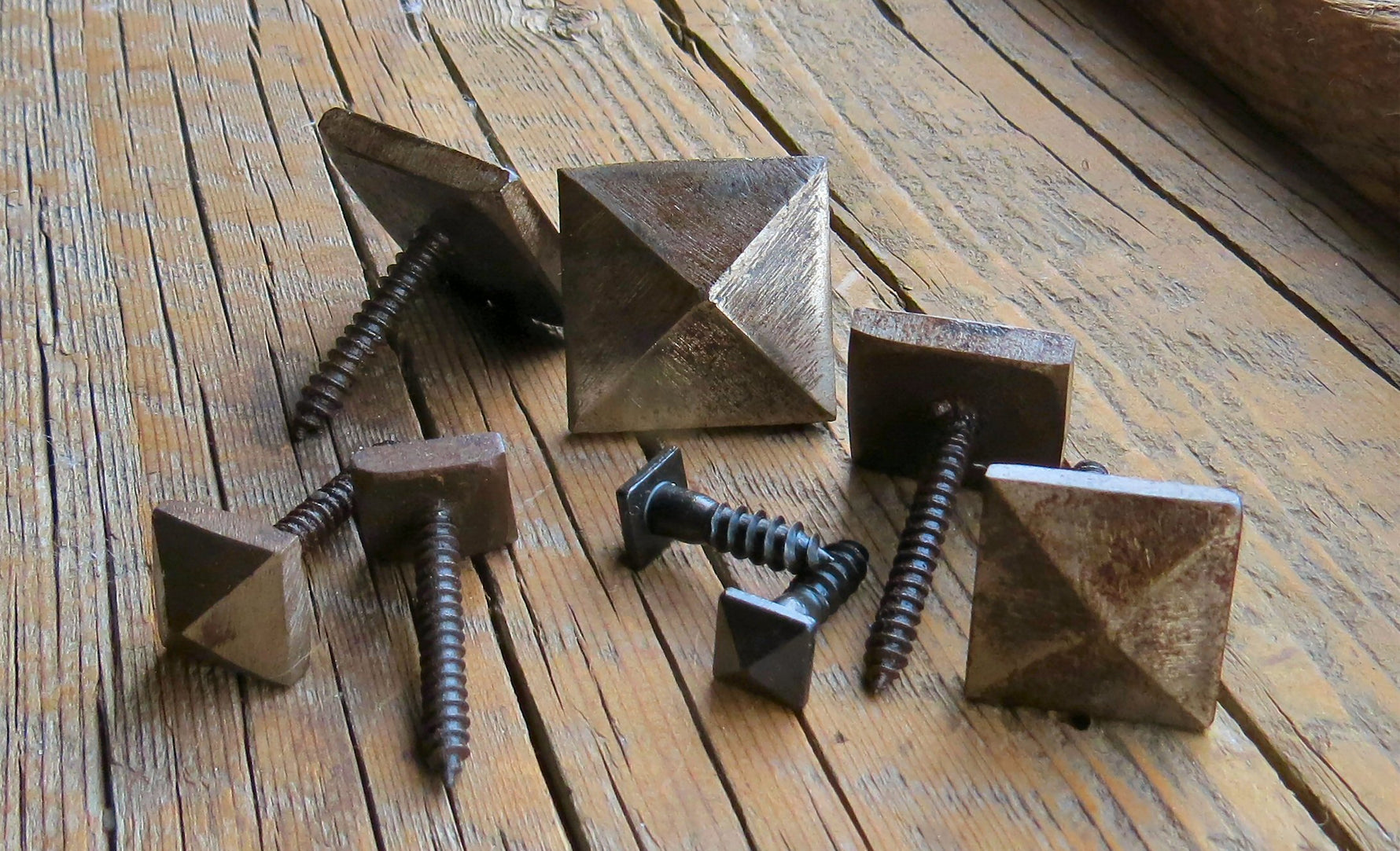 A set of smooth pyramid head screws with varying finishes, displayed on a wooden surface.