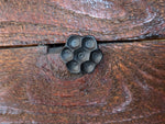 A close up of he flower head lag screw with a black finish installed in barnwood.