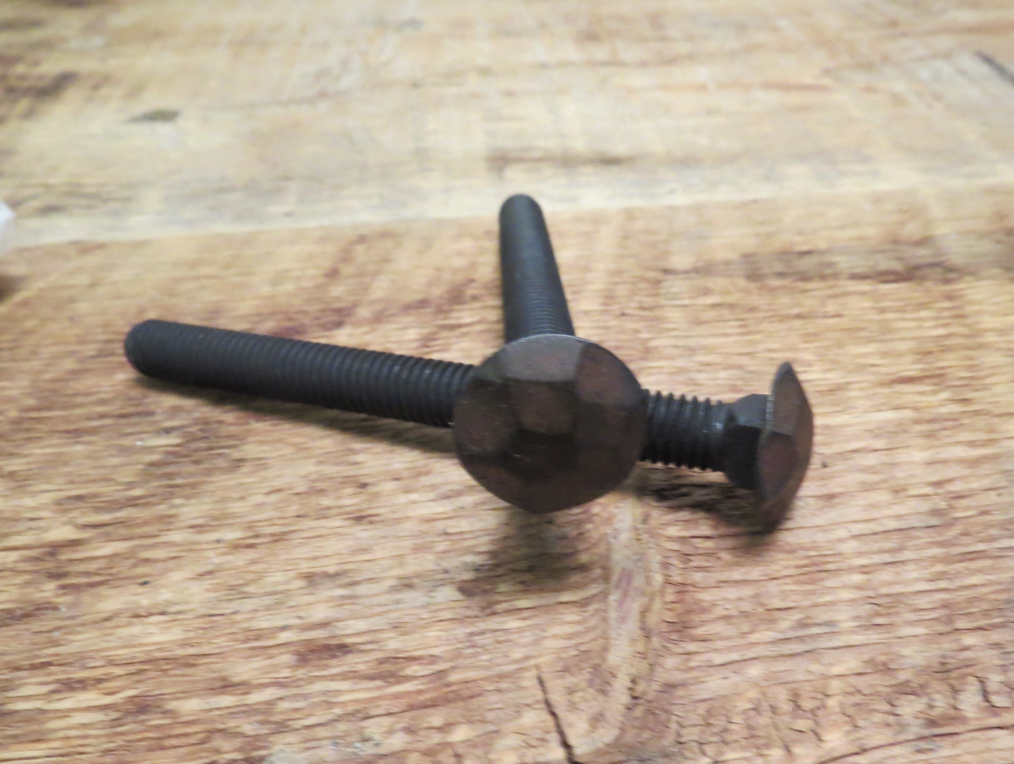 A top and side view of hammered carriage bolts that are black and finished with an oil rubbed bronze patina.