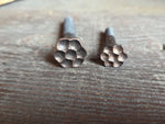 fancy flower head lag screws side by side on a wooden surface