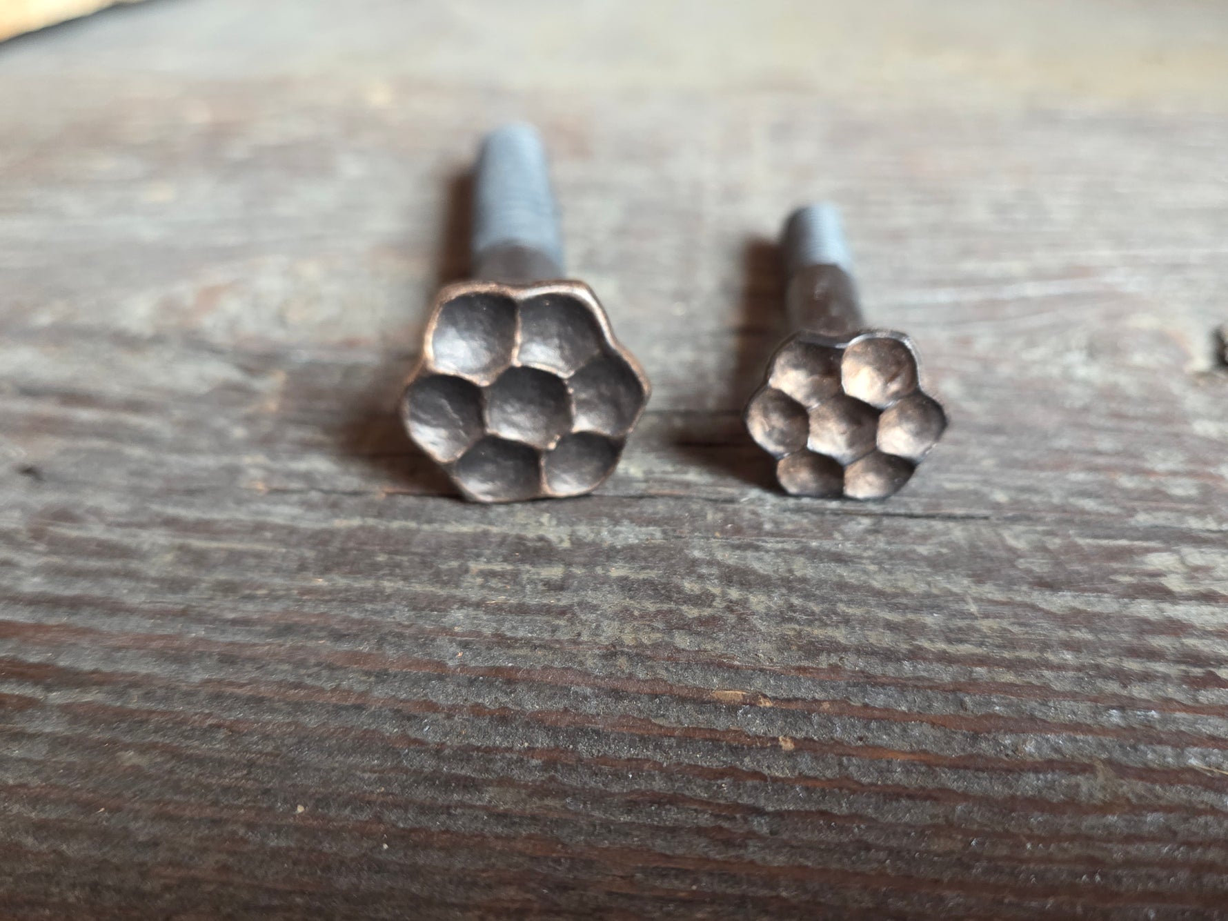 fancy flower head lag screws side by side on a wooden surface