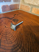 A side view of an ornate tapered square head bolt with a raw finish on a wood background.