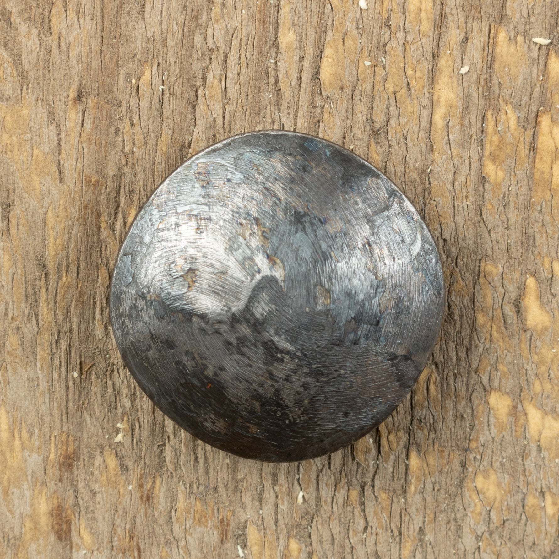 A top view of a carriage bolt that has a smooth texture and a raw metal finish.