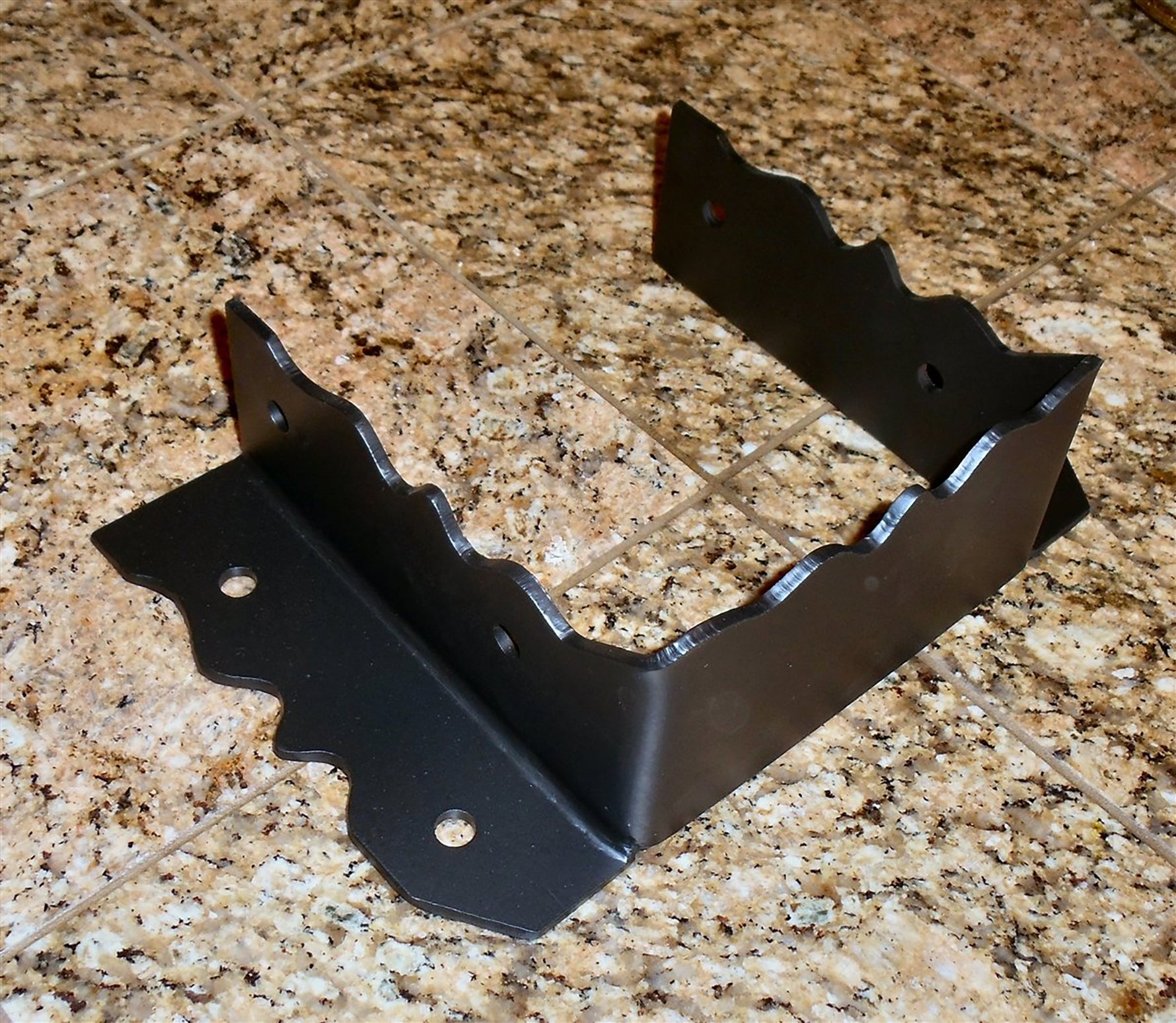 A black iron joist hanger with a decorative design.