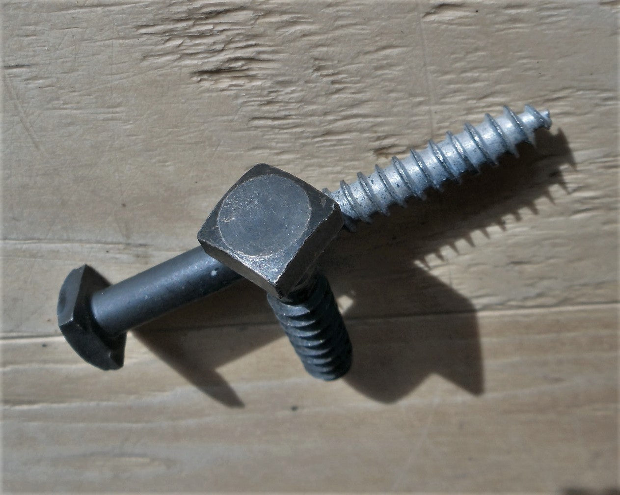 2 smooth square head lag with an oil rubbed bronze finish on a piece of wood as the background