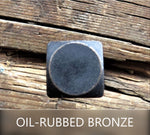 1/4" Dia. Smooth Square Head Bolt Nuts painted black with oil rubbed bronze patina on a wood background.