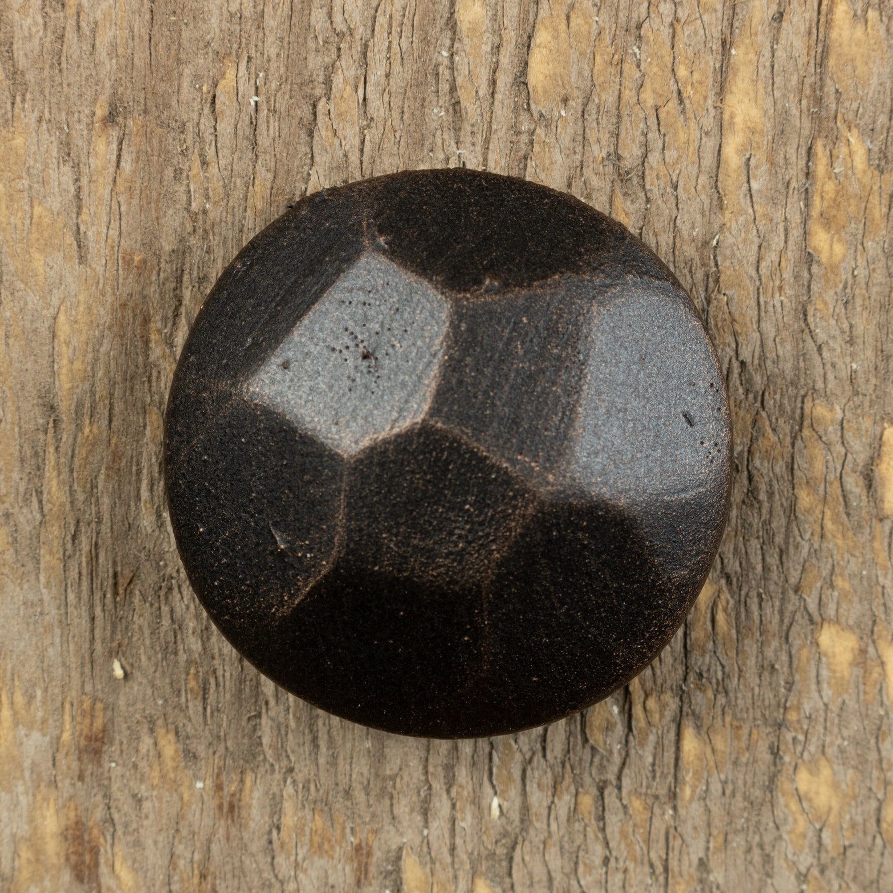 A top view of a hammered carriage bolt that has been painted back and has an oil rubbed bronze patina finish.