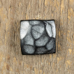 A hand hammered square head bolt that has been painted black and finished with an aged pewter patina.