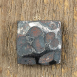 A hand hammered square head bolt that has a raw finish installed on a wood background.