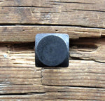 A top view of a smooth textured square head bolt with black oxide finish installed on a wood background.