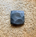 A square head lag hand hammered painted black with a pewter finish screwed in a wood background 