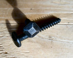 A black square pyramid head decorative screw on a wooden surface.