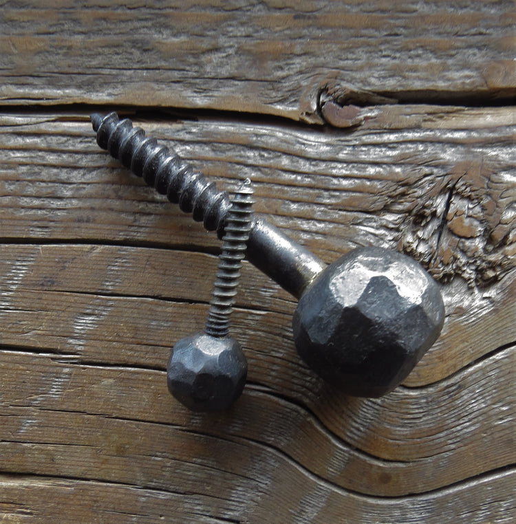 A hammering ball head lag screw with a textured surface, displayed against a wooden background.